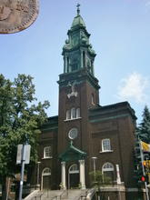 Two-story, brown brick church with a central tower housing the entry. 